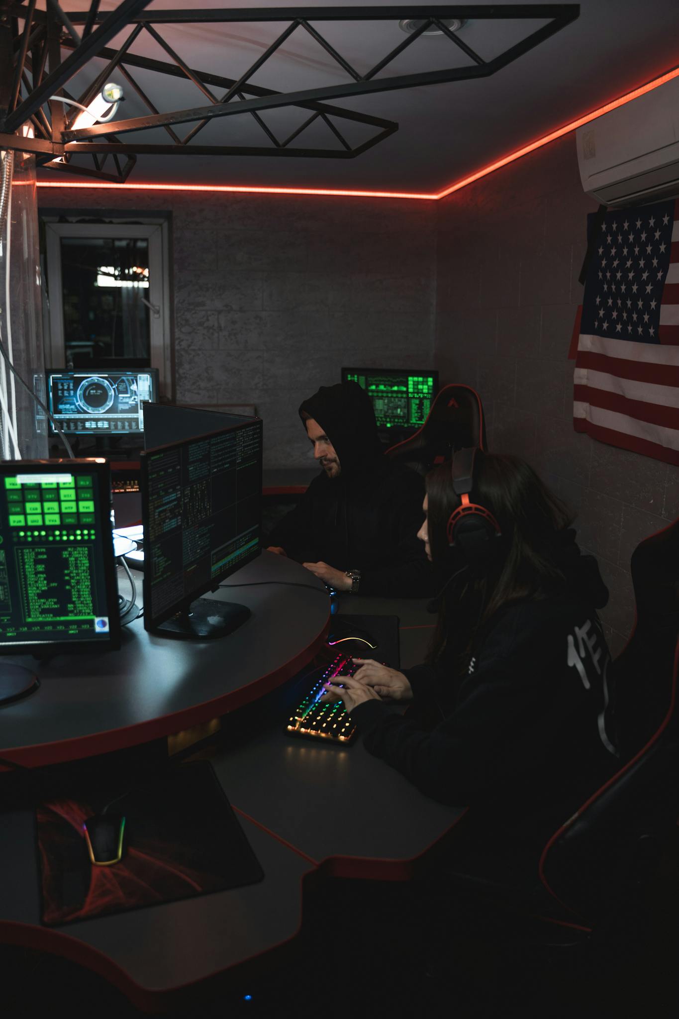 Hackers in a dim room working on cyber security systems with multiple screens and digital data.